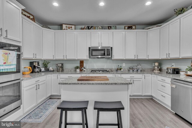 9937 Sodus Ct, Faulkner, MD 20632 - kitchen with a breakfast bar, white cabinetry, light wood-type flooring, and appliances with stainless steel finishes