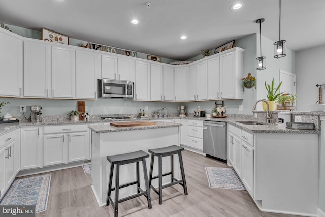 9937 Sodus Ct, Faulkner, MD 20632 - kitchen featuring a breakfast bar, light wood finished floors, a sink, white cabinetry, and stainless steel appliances