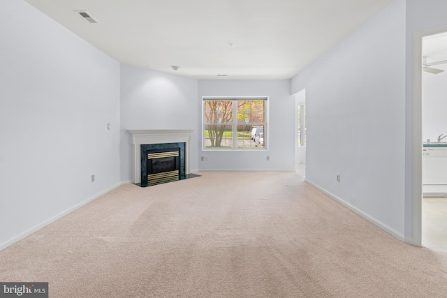 unfurnished living room featuring a high end fireplace, baseboards, carpet flooring, and visible vents