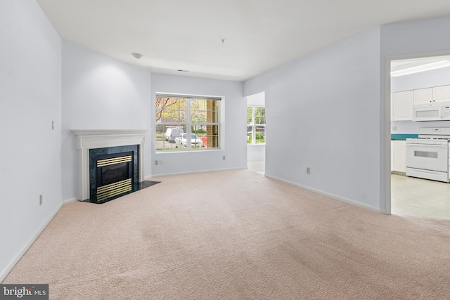 unfurnished living room with a premium fireplace, baseboards, and light colored carpet