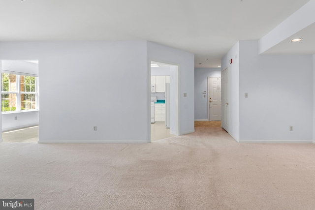 unfurnished living room with baseboards, light carpet, and recessed lighting