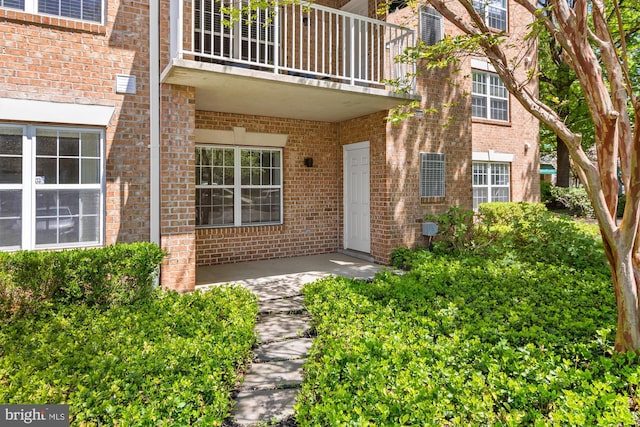 property entrance with brick siding and a balcony