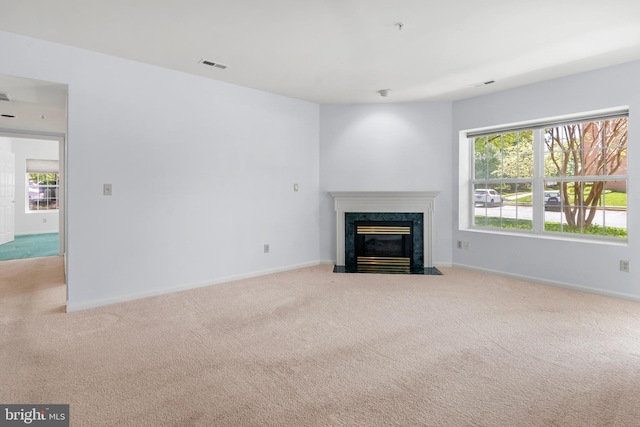 unfurnished living room with visible vents, a high end fireplace, and carpet