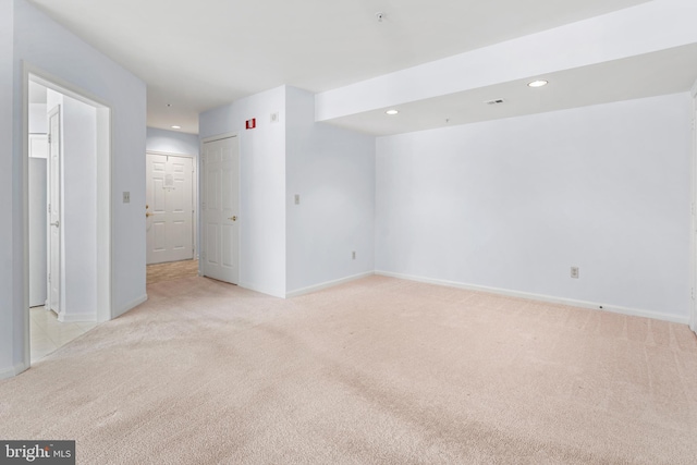 empty room with light colored carpet, recessed lighting, and baseboards
