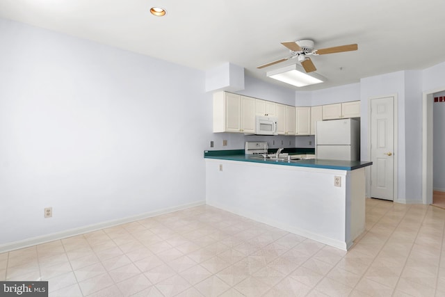 kitchen with a peninsula, dark countertops, a ceiling fan, and white appliances