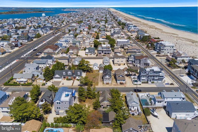 drone / aerial view featuring a water view, a beach view, and a residential view
