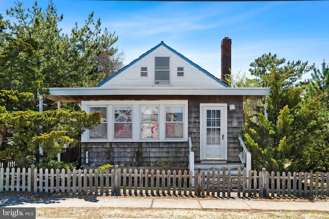 view of front facade with a fenced front yard and a chimney
