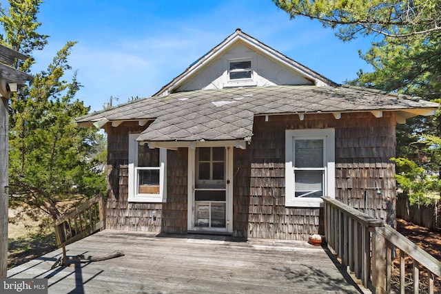 exterior space with a wooden deck and roof with shingles