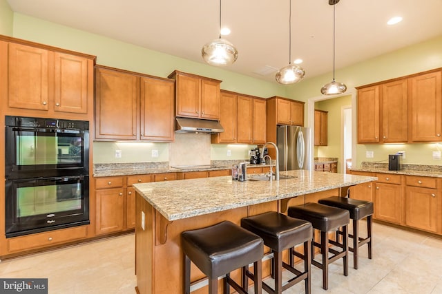 kitchen featuring a sink, brown cabinetry, light tile patterned flooring, black appliances, and under cabinet range hood