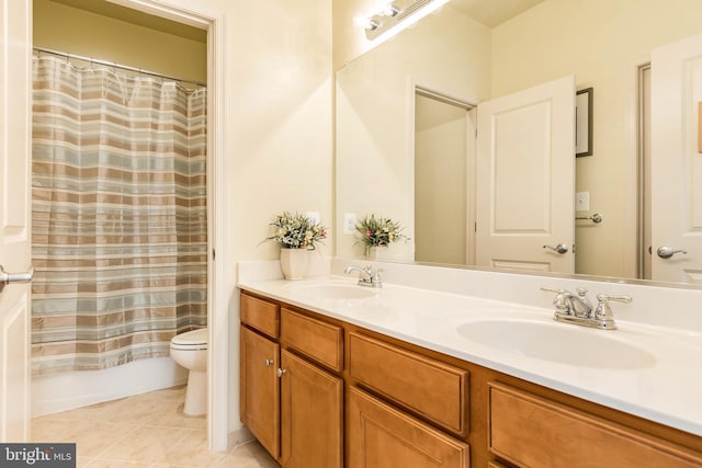 bathroom with a sink, double vanity, toilet, and tile patterned floors