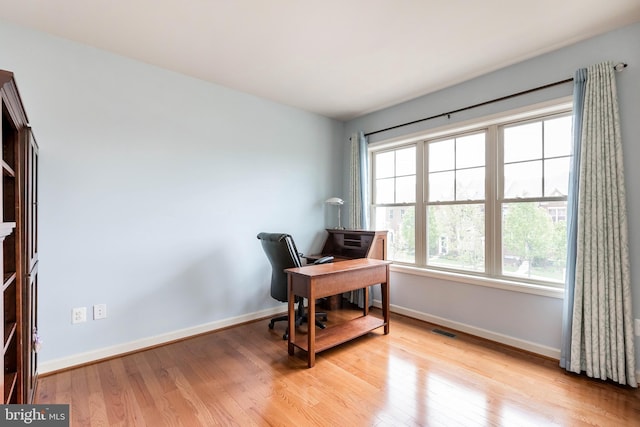 office space featuring light wood-style floors, visible vents, and baseboards