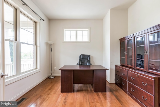office space featuring baseboards, light wood-style floors, and visible vents