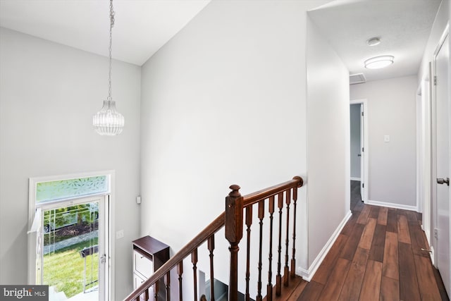 hall with baseboards, a notable chandelier, dark wood-type flooring, and an upstairs landing