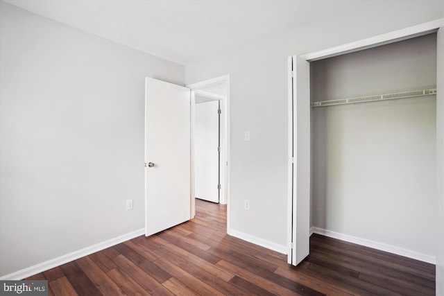unfurnished bedroom featuring baseboards, a closet, and dark wood-style flooring