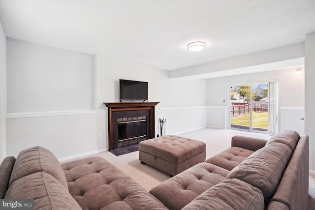 living area featuring baseboards, a fireplace with flush hearth, and carpet