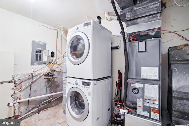clothes washing area featuring laundry area, stacked washer and clothes dryer, and electric panel