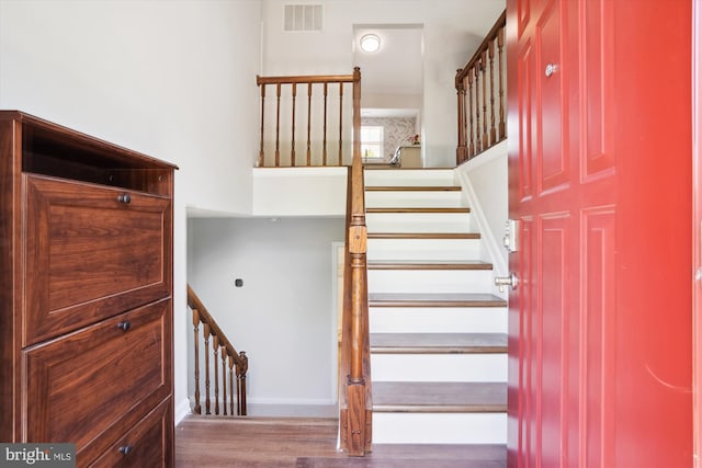 stairway featuring baseboards, visible vents, and wood finished floors