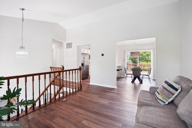 corridor featuring dark wood-style flooring, high vaulted ceiling, a chandelier, an upstairs landing, and visible vents