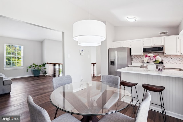 dining room featuring visible vents, baseboards, dark wood-style floors, and high vaulted ceiling