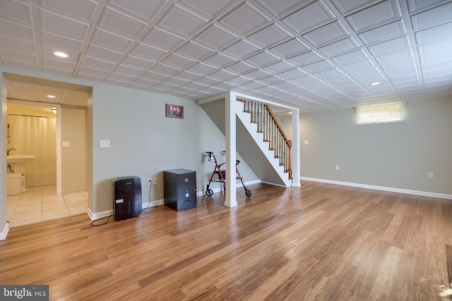 below grade area featuring recessed lighting, baseboards, stairway, and light wood-type flooring