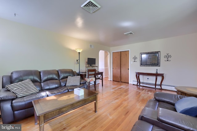 living area with arched walkways, a baseboard radiator, and visible vents