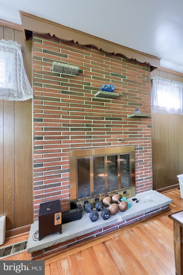 room details featuring visible vents, wood finished floors, wooden walls, and a fireplace