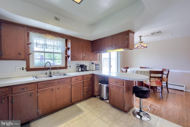 kitchen featuring visible vents, open shelves, a sink, a baseboard heating unit, and a peninsula