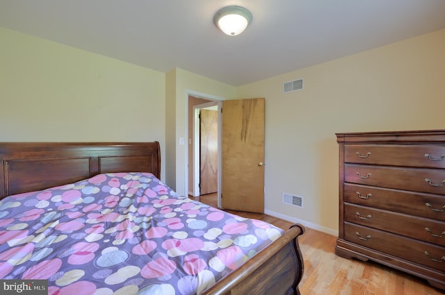 bedroom featuring baseboards, wood finished floors, and visible vents