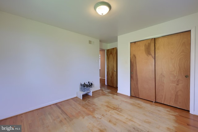 unfurnished bedroom featuring baseboards, visible vents, light wood finished floors, and a closet