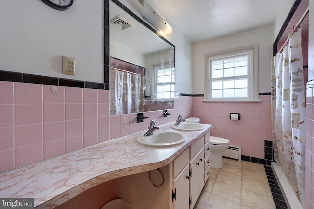 full bath featuring visible vents, a sink, a baseboard heating unit, and tile walls