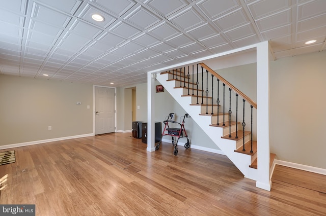 basement with baseboards, recessed lighting, light wood finished floors, and stairway