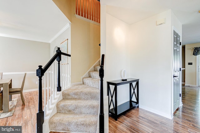 staircase with baseboards, ornamental molding, and wood finished floors