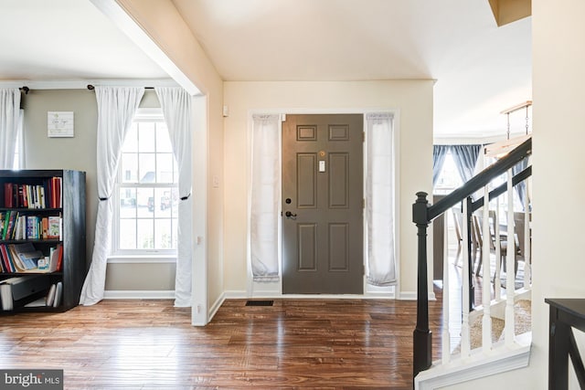 foyer entrance featuring baseboards, wood finished floors, a healthy amount of sunlight, and stairway