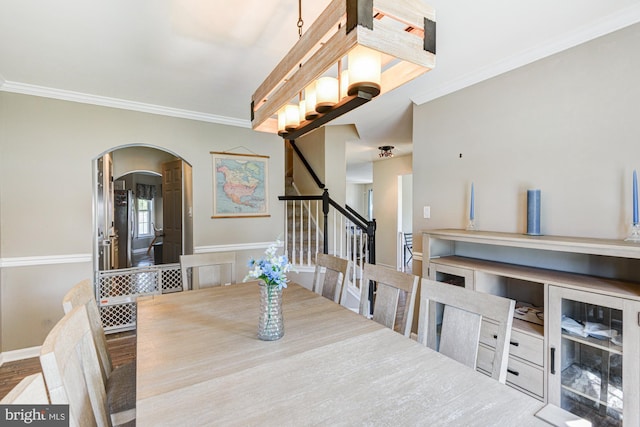 dining area with crown molding, arched walkways, and stairway
