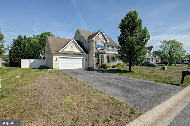 traditional-style house featuring fence, a front yard, stone siding, an attached garage, and driveway