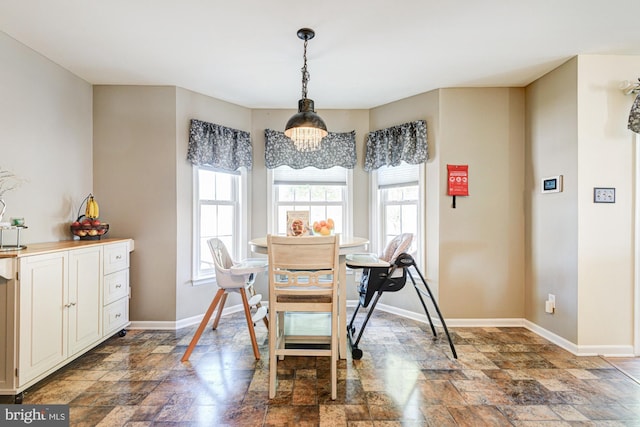 dining space with baseboards, a wealth of natural light, and stone finish floor