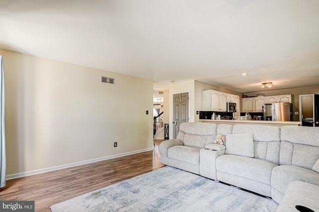 living room featuring light wood finished floors, stairs, recessed lighting, baseboards, and visible vents