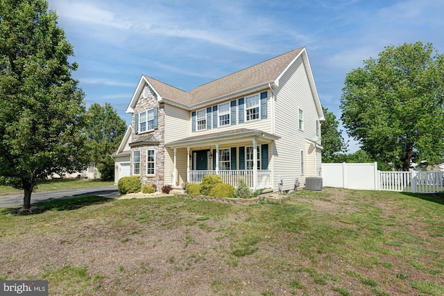 traditional-style home featuring a porch, fence, a front yard, and cooling unit