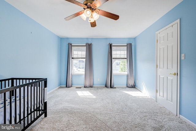 unfurnished bedroom featuring baseboards, carpet flooring, a nursery area, and multiple windows