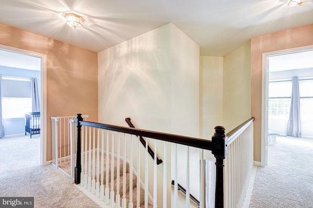 hall featuring carpet flooring and an upstairs landing