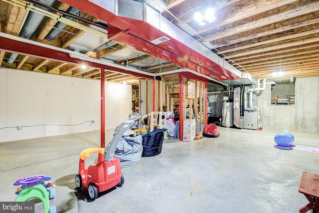unfinished below grade area with heating unit, visible vents, and gas water heater