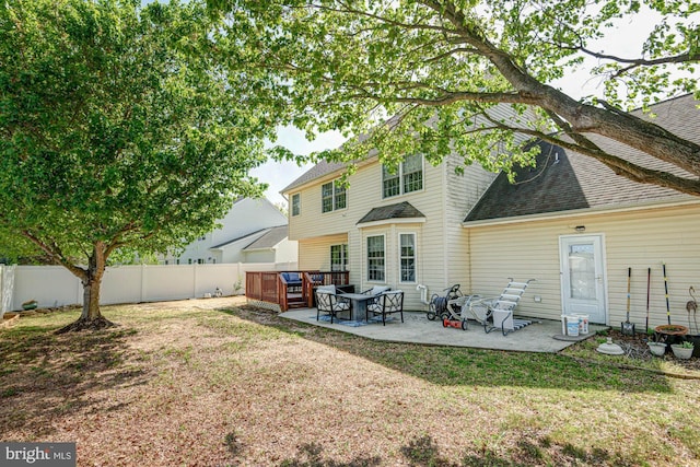 rear view of house featuring a fenced backyard, a shingled roof, a yard, and a patio area
