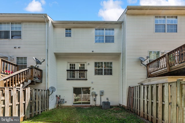 rear view of house featuring a yard, stairway, and a fenced backyard