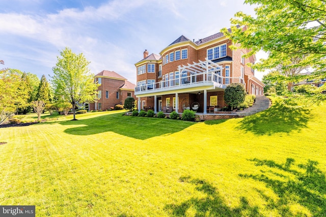 rear view of property featuring a lawn, a chimney, a deck, and brick siding