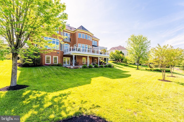rear view of house with a lawn, brick siding, and french doors