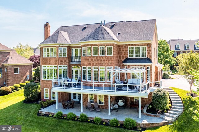 rear view of house with a lawn, a patio, a chimney, and brick siding