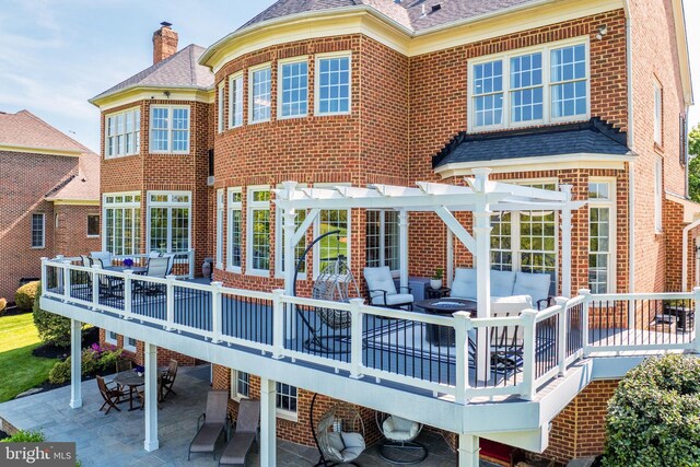 rear view of property featuring a pergola, brick siding, an outdoor hangout area, a deck, and outdoor dining area