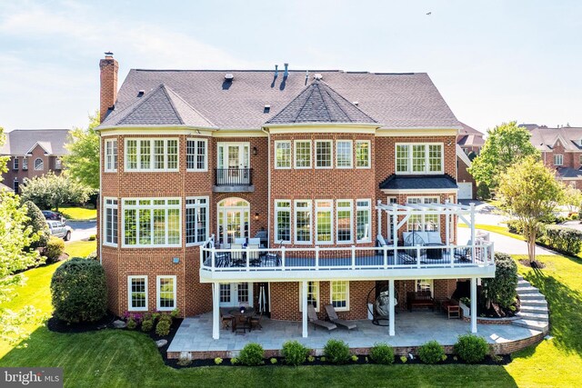 back of property with a patio, a lawn, a chimney, and brick siding