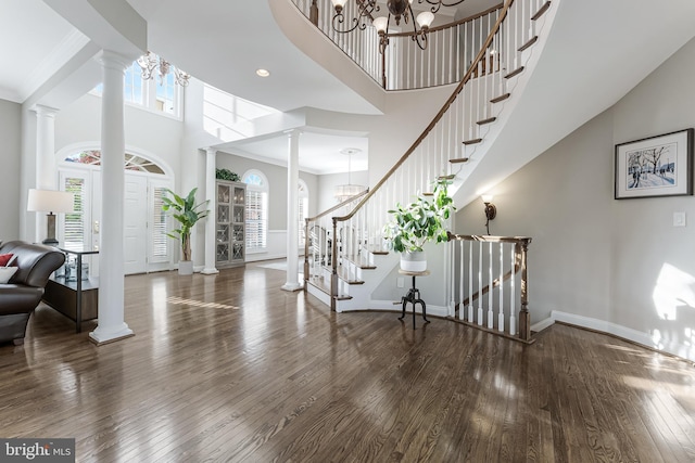 foyer featuring a high ceiling, decorative columns, and a notable chandelier