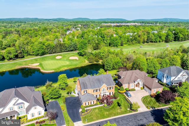 drone / aerial view with a water view, a view of trees, golf course view, and a residential view